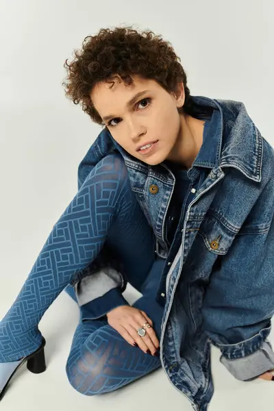 A striking young woman poses gracefully in a denim outfit, highlighting modern fashion trends. — Stock Photo