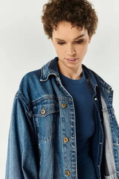 A stylish young woman showcases her trendy outfit while posing gracefully in a bright studio. — Stock Photo