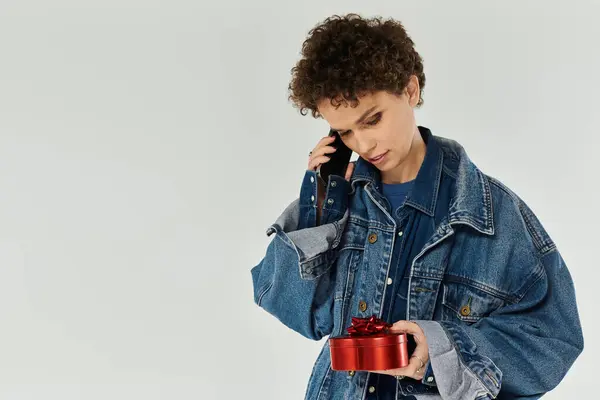 Eine junge schöne Frau mit lockigem Haar telefoniert in einer roten Geschenkbox. — Stockfoto