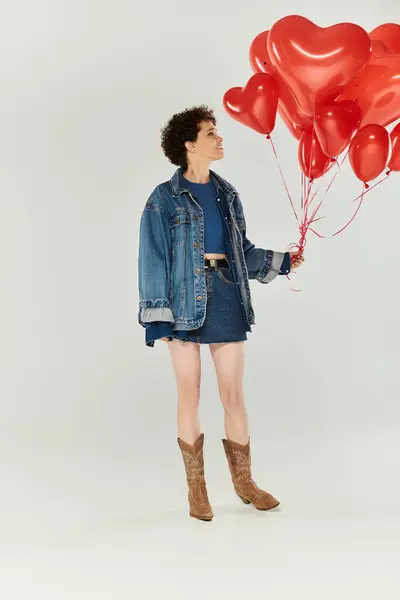 Eine Frau strahlt in ihrem stylischen Outfit Zuversicht aus und hält fröhlich leuchtende Herzballons in den Händen. — Stockfoto