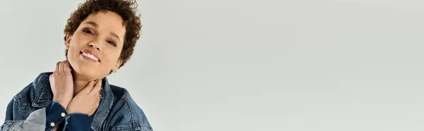 A young woman smiling brightly while adjusting her collar, showcasing her fashionable style. — Stock Photo