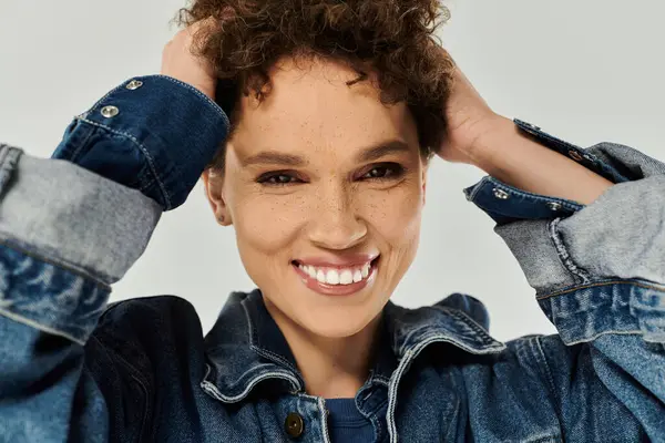 A young woman with curly hair smiles, flaunting her style in denim. — Stock Photo