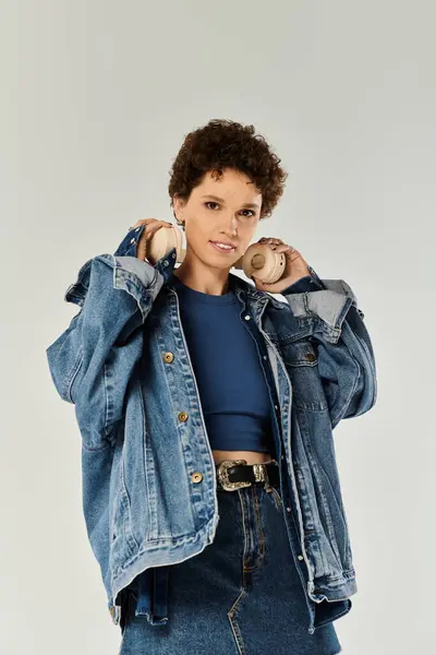 Casual yet stylish young woman poses in a studio, wearing a denim jacket and showing confidence. — Stock Photo