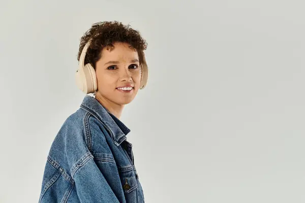 A young woman smiles brightly, enjoying her favorite music and showing off her style. — Stock Photo