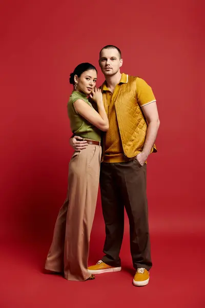 A young couple dressed in fashionable outfits shares a tender moment in a vibrant studio. — Stock Photo