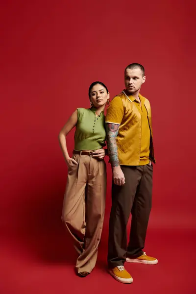A beautiful young couple dressed in trendy outfits poses together in a bold studio backdrop. — Stock Photo