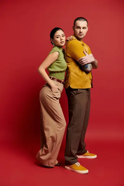 A beautiful couple dressed in trendy outfits poses together in a vibrant studio, celebrating love. — Stock Photo