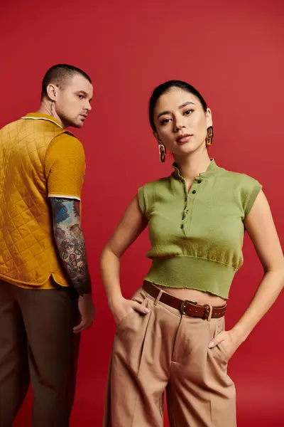 A fashionable couple poses together in a studio with a bold red backdrop, radiating romance. — Stock Photo