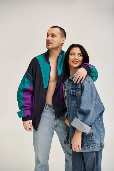 A beautiful couple dressed in trendy outfits shares a joyful moment in a studio setting. — Stock Photo