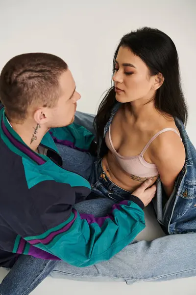 A young couple dressed in trendy outfits shares an intimate moment in a studio, celebrating love. — Stock Photo