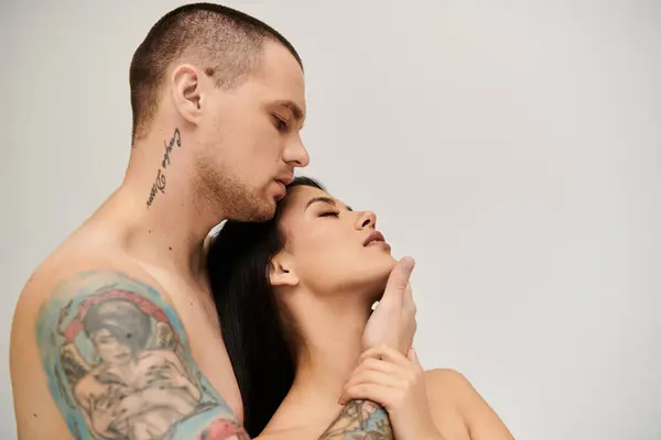 A seductive young woman leans into her shirtless partner, sharing an intimate moment. — Stock Photo