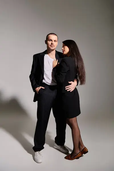 A beautiful young couple showcases their stylish outfits, radiating love and connection in a studio. — Stock Photo