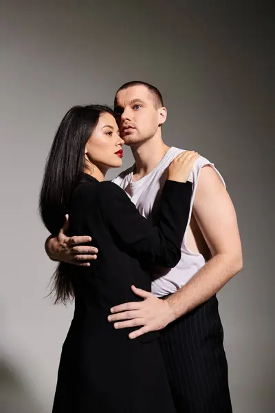 A young couple in fashionable attire shares an intimate moment in a studio setting, exuding love. — Stock Photo