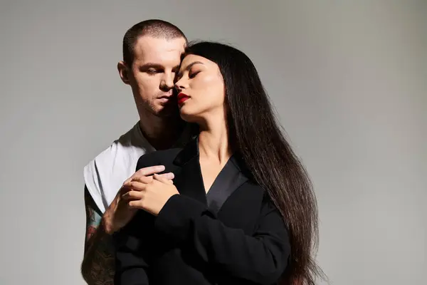 A beautiful couple dressed in fashionable clothes shares an intimate moment in the studio. — Stock Photo