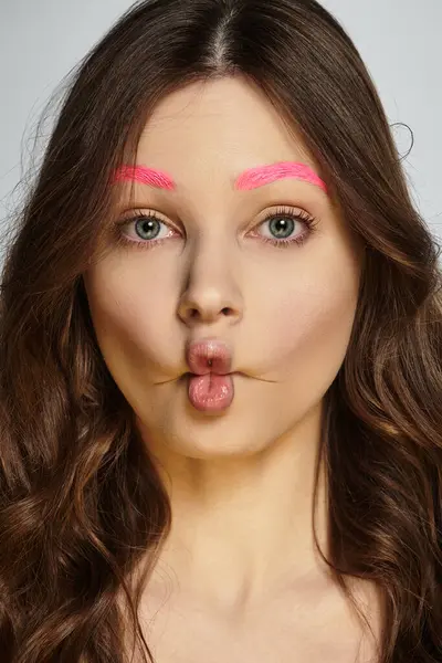 A young woman flaunts her bold style with striking pink eyebrows in a studio pose. — Stock Photo