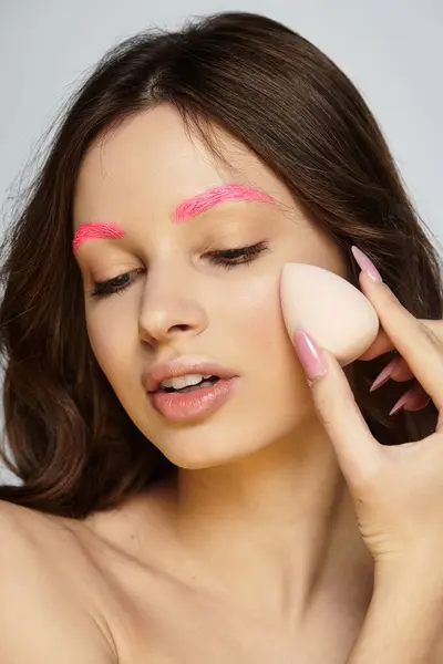Young woman showcases unique style with striking pink eyebrows against a soft grey backdrop. — Stock Photo