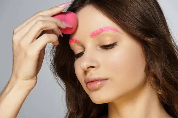 Mulher jovem mostra seu estilo de beleza único com sobrancelhas cor-de-rosa vibrantes, realçando seu olhar. — Fotografia de Stock