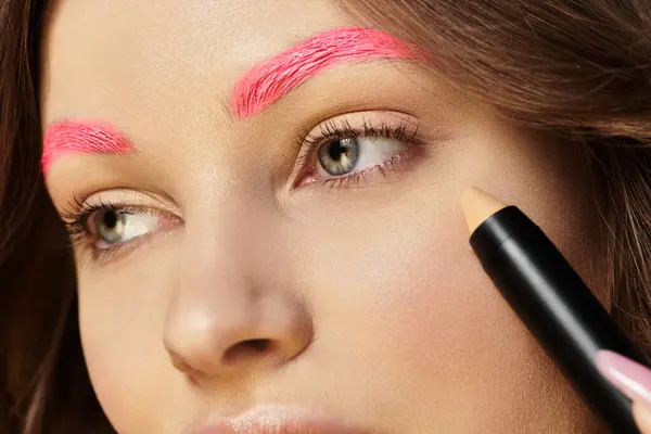Attractive young woman showcases her striking pink eyebrows while enhancing her beauty look. — Stock Photo
