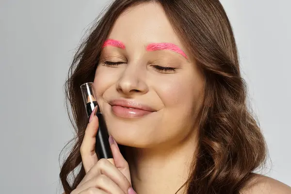 Jeune femme exprime son style unique et sa confiance avec des sourcils roses vibrants en studio. — Photo de stock