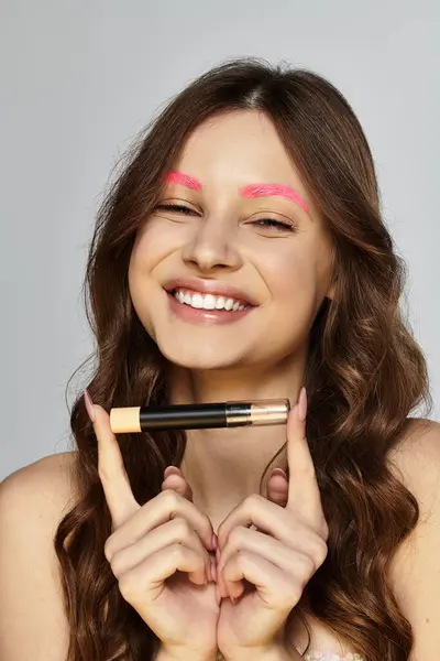Attrayant jeune femme met en valeur sa beauté avec les sourcils roses et le charme ludique dans un studio. — Photo de stock