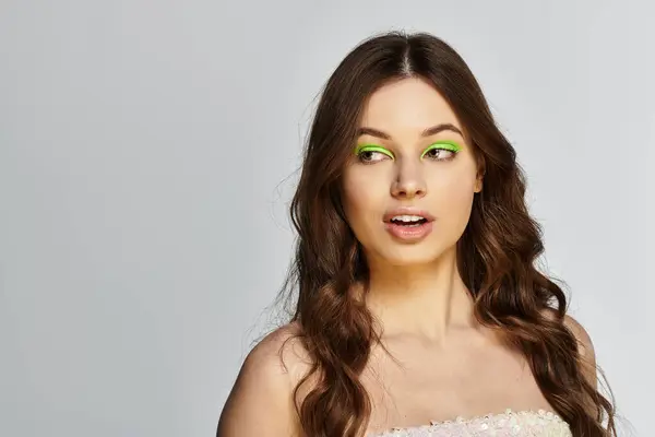 Young woman showcases her striking beauty with vibrant green eyeshadow against a grey backdrop. — Stock Photo