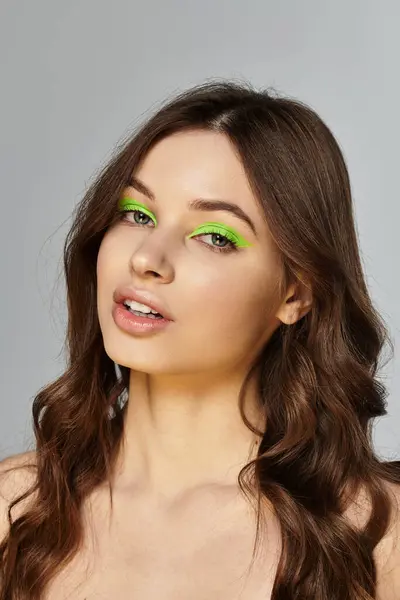 Young woman with vibrant green eyeshadow showcases her striking beauty and bold style in a studio. — Stock Photo