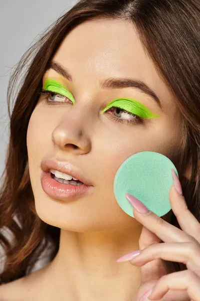 Une jeune femme met en valeur son fard à paupières vert vif et son maquillage audacieux, soulignant son style. — Photo de stock