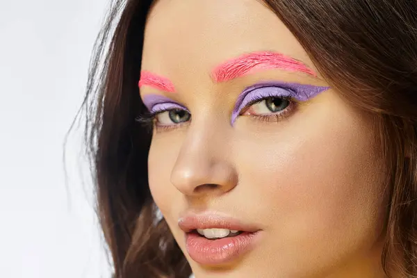 Jeune femme présente son magnifique fard à paupières violet et ses sourcils roses dans un studio créatif. — Photo de stock