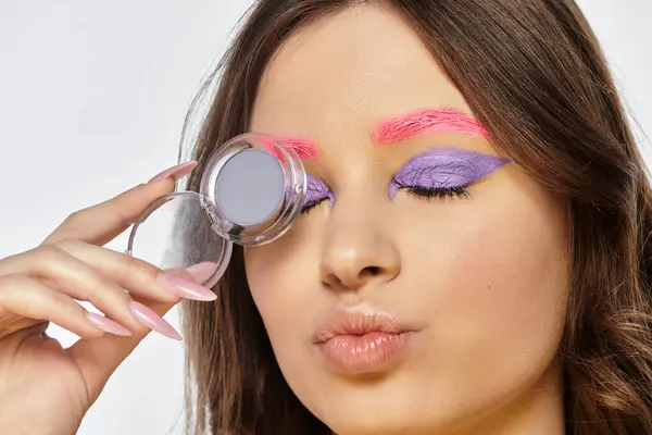 Mujer joven bonita muestra llamativa sombra de ojos púrpura y cejas rosadas en una exhibición artística. — Stock Photo