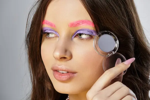 A young woman showcases her beauty with bold purple eyeshadow and pink eyebrows in a studio. — Stock Photo