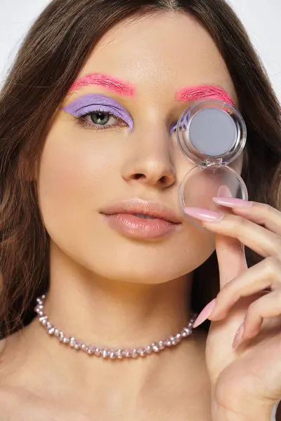 Una joven mujer muestra su aspecto de maquillaje audaz con sombra de ojos púrpura y cejas rosadas. — Stock Photo