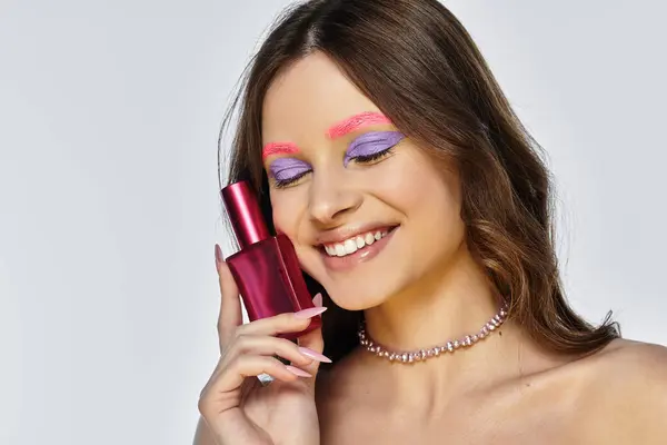 Young woman with stunning purple eyeshadow and pink eyebrows poses confidently in a sleek studio. — Stock Photo