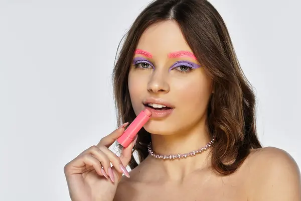 A young woman showcases her stunning bold makeup with vibrant purple eyeshadows and pink eyebrows. — Stock Photo