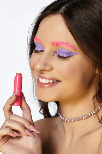 Una joven muestra su creatividad con llamativa sombra de ojos púrpura y cejas rosadas en un estudio. — Stock Photo