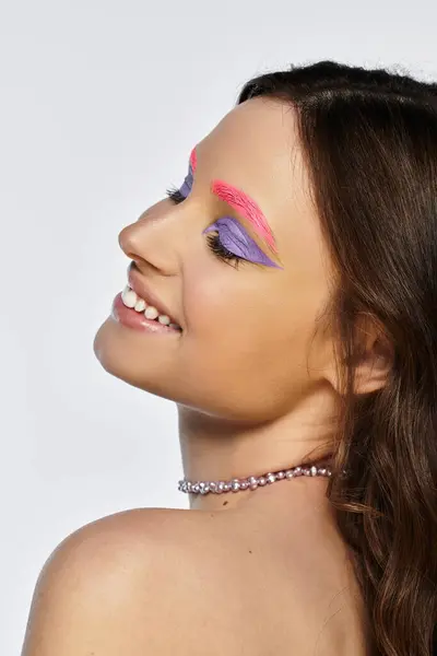 A young woman showcases vibrant purple eyeshadows and pink eyebrows, radiating confidence. — Stock Photo