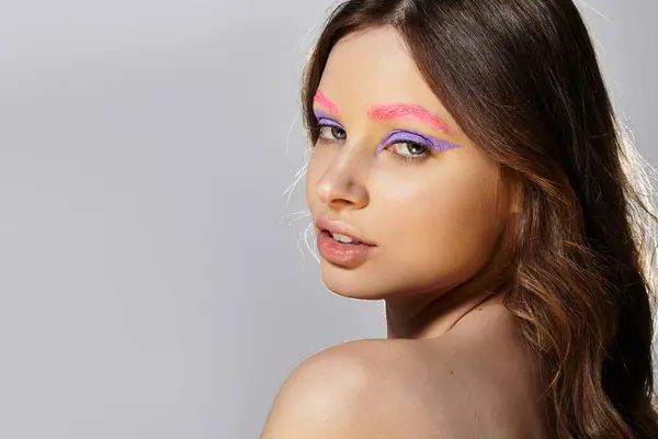 A young woman showcases her striking purple eyeshadows and pink eyebrows in bold makeup. — Stock Photo