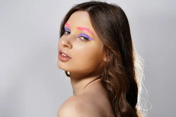 Jeune femme met en valeur sa créativité avec des couleurs de maquillage pastel frappantes dans un contexte neutre. — Photo de stock