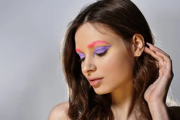 A pretty young woman showcases striking purple eyeshadow and pink eyebrows in a creative display. — Stock Photo