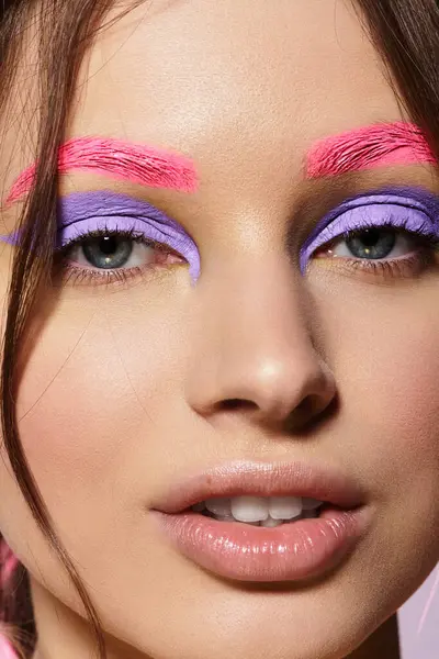 Jeune femme met en valeur le maquillage artistique avec des fards à paupières violettes et des sourcils roses en studio. — Photo de stock