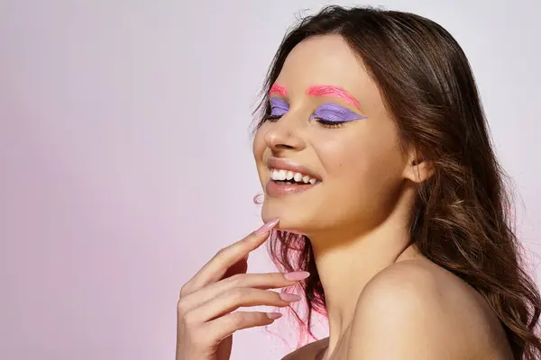 Une jeune femme confiante sourit avec un maquillage audacieux, mettant en valeur des sourcils vibrants et un fard à paupières. — Photo de stock