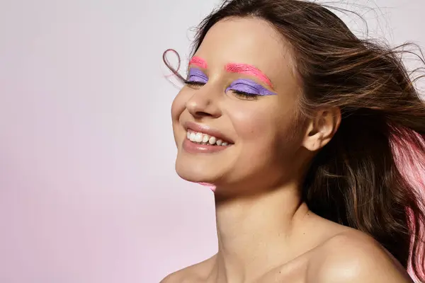 Young woman showcases stunning purple and pink makeup in a vibrant studio atmosphere. — Stock Photo