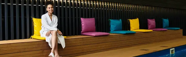 A young african american woman smiles gently while seated on a stylish bench at the spa. — Stock Photo