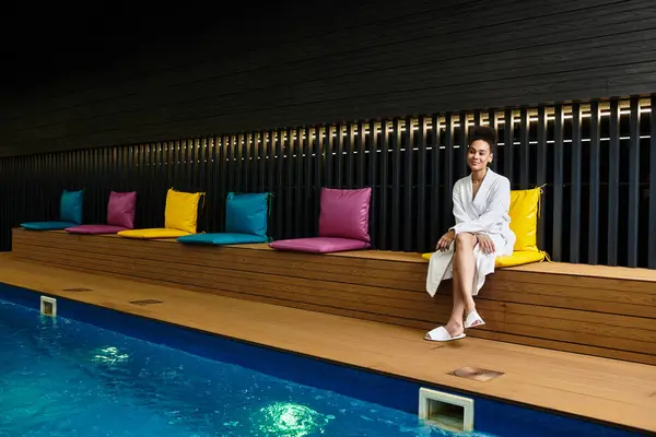 A young african american woman sits peacefully at a stylish spa, embracing the calm surroundings. — Stock Photo
