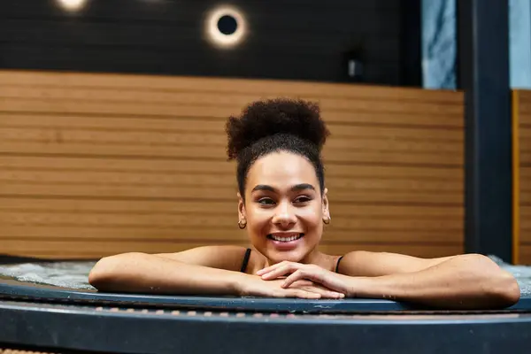 Une jeune Afro-Américaine profite de la détente dans un cadre spa tranquille, souriant joyeusement. — Photo de stock