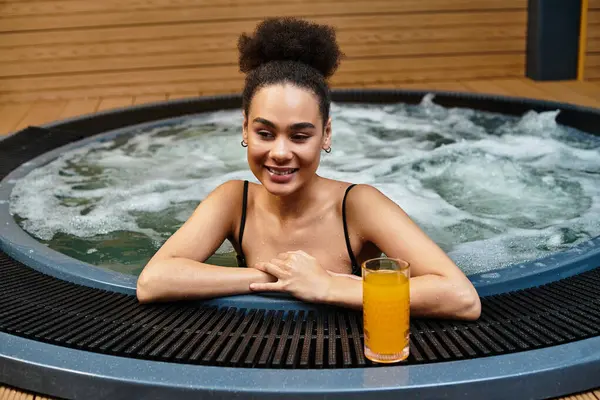 A beautiful young woman relaxes in a spa jacuzzi while savoring a drink, embracing tranquility. — Stock Photo