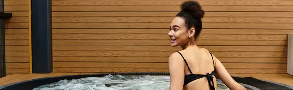 A young African American woman smiles while enjoying a tranquil moment in a spa hot tub. — Stock Photo