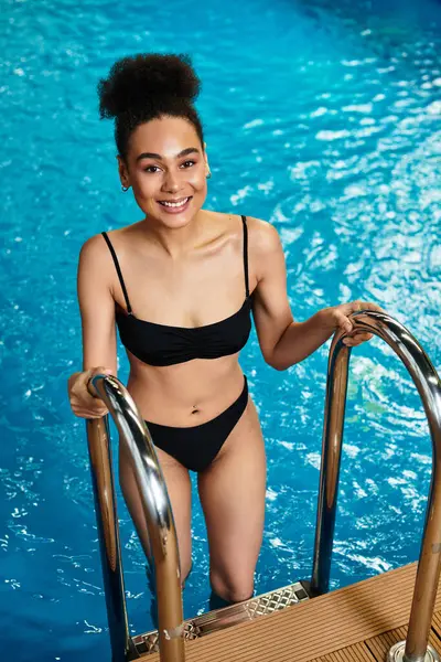 Uma jovem alegre sorri enquanto sai da serena piscina de spa, personificando relaxamento. — Fotografia de Stock