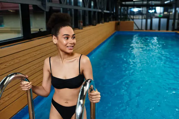 Beautiful young woman embraces tranquility in a luxurious spa, stepping into inviting pool waters. — Stock Photo