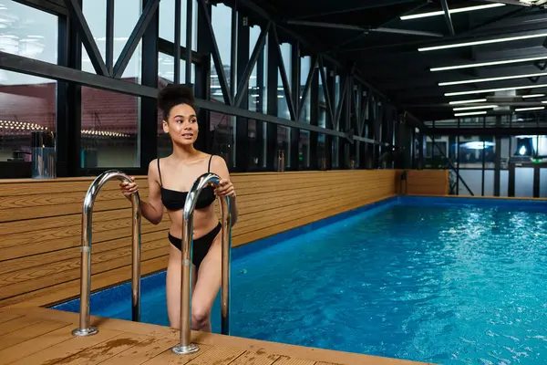 A beautiful young woman steps out of the refreshing spa pool, embracing tranquility and wellbeing. — Stock Photo