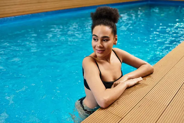 A young African American woman enjoys a calming experience in the spa, surrounded by water. — Stock Photo